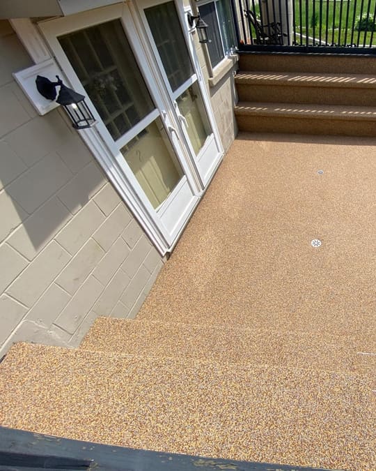 A raised deck landing and stair treads finished in honey-gold Gator Grip with a brown border