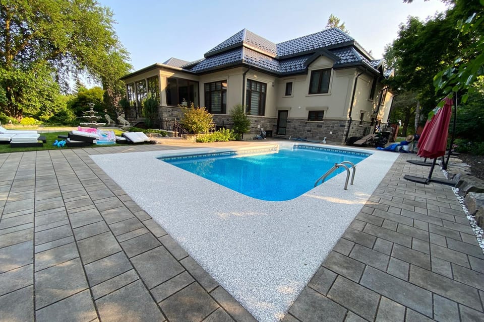 The same pool deck after Gator Grip: a pearl-white non-slip rubber surface with a charcoal border