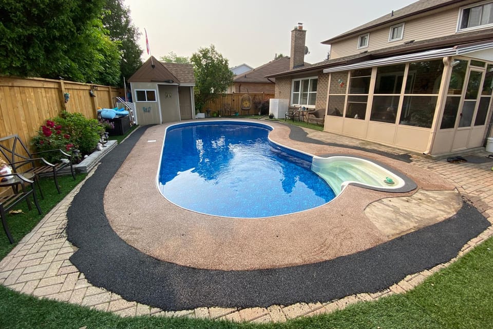 Pool deck before resurfacing: mismatched tan concrete, a black asphalt patch and brown staining ringing the pool
