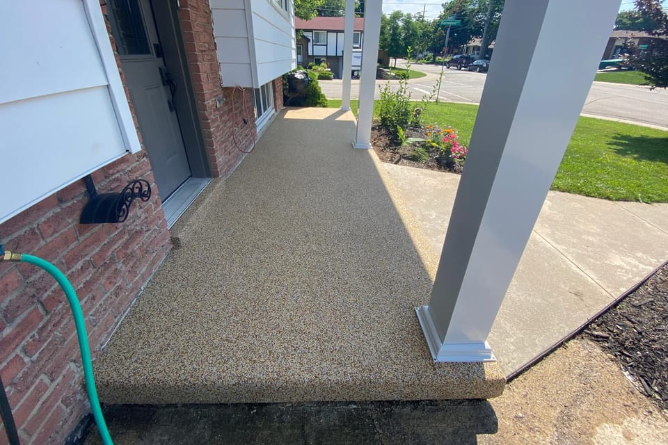 The same front porch after Gator Grip: an even beige rubber surface across the porch and steps
